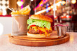 Huge Cheeseburger With Large Meat Patty, Green Lettuce, Red Tomato, Cucumber, Plenty Of Tasty Cheese And Sauce. Hot Spicy Burger With Crispy Fries On Wooden Surface. Food From American Diner 50s.
