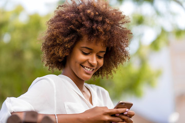 Canvas Print - Outdoor portrait of a Young black African American young woman texting  on mobile phone