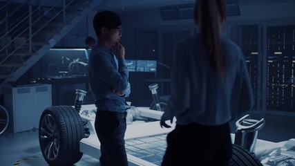 Poster - Camera Walkthrough in a Development Laboratory Room with Diverse Professional Team of Engineers and Scientists Working on a Electric Car Chassis with Wheels, Batteries, Engine and Suspension. 