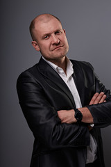 Wall Mural - Serious bald business man with folded arms in suit on grey background. Closeup