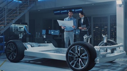 Poster - Auto Industry Design Facility: Male Chief Engineer Shows Car Blueprints Female Software Design and Integration Engineer. Electric Vehicle Platform Chassis Concept Has Wheels, Engine and Battery 
