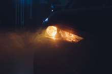 In The Automobile Salon Garage, Center The Headlights Of The Car Are Very Close, Turning On Turning Off Checking The Front Light Dimensions . Concept Of: Headlight Testing, New, Diagnostics, Car.