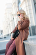 © Galina Zhigalova - Stylish fashionable blonde woman wearing coat and sunglasses speaking on mobile phone, street style photo