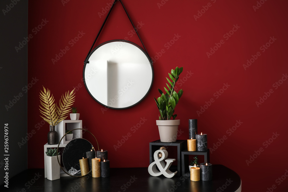 Table with decor and mirror hanging on color wall