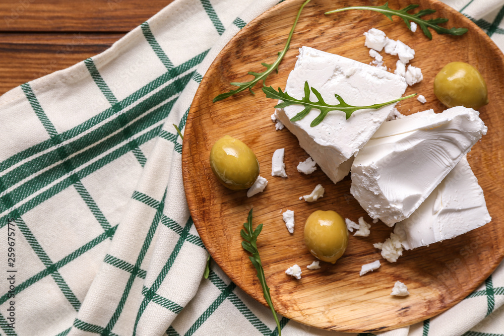 Plate with tasty feta cheese and olives on table