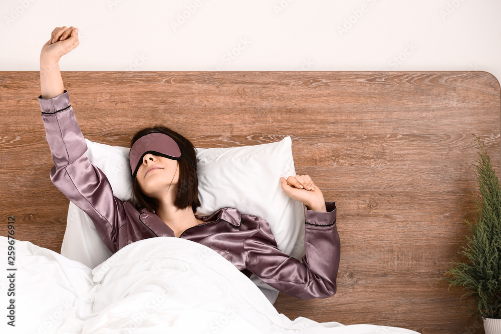 Young woman with sleep mask in bed