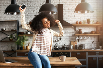 Wall Mural - African-American woman listening to music in kitchen