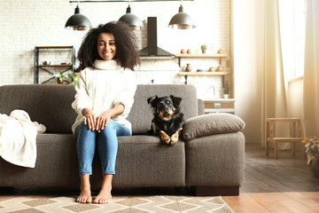 Wall Mural - Beautiful African-American woman with cute dog at home