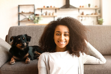 Wall Mural - Beautiful African-American woman with cute dog at home