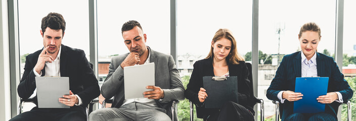 Businesswomen and businessmen holding resume CV folder while waiting on chairs in office for job interview. Corporate business and human resources concept.