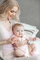 Wall Mural - Young mother with her little cute baby daughter. Little baby girl and her mom. Mama with her child indoor.