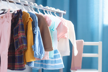 children's cloth rack, selective focus. pastel color children's clothes in a row on open hanger indo
