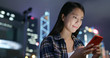 © leungchopan - Woman use of mobile phone in city at night