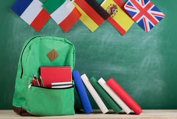 Fototapete - backpack, flags of Spain, France, Great Britain and other countries, books and school supplies of the blackboard