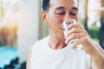 Wall Mural - Senior man drink mineral water in gym fitness center after exercise. Elderly healthy lifestyle.