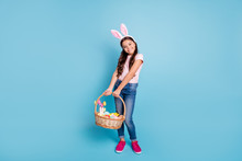Full Length Body Size Photo Of Cheerful  Dreamy Careless Beautiful Charming Pretty Long-haired Girl Jeans Outfit Showing Big Wooden Basket Full Of Painted Colored Eggs Isolated Pastel Pop Background