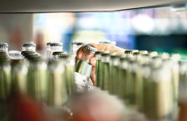 Close up of drink shelf in supermarket. Alcohol, soda, sodapop, mineral water or ginger ale bottle. Customer buying product in grocery store or liquor shop. Retail worker filling and stocking shelves.