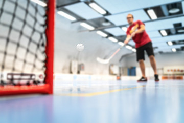 Floorball training on court. Man training floor hockey in arena. Slap shot on goal.