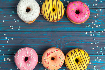 Poster - Colorful fresh donuts on dark blue wooden surface