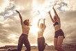 © simona - Happiness and joy for sport success active lifestyle - group of pretty females friends jumping on the air together for victory - outdoor beach sport concept and cloudy sunset background