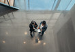 © JonoErasmus - Two business people standing in the open spaced lobby of an office looking at a tablet