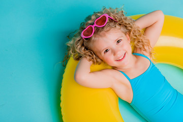 Wall Mural - Cute girl in swimsuit holding swimming circle. Isolated on blue background .Summer holidays - pretty girl with inflatable ring 