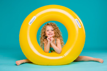 Wall Mural - Cute girl in swimsuit holding swimming circle. Isolated on blue background .Summer holidays - pretty girl with inflatable ring 