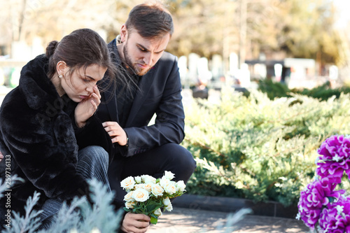 Fotomural Couple putting flowers on grave of their relative at funeral