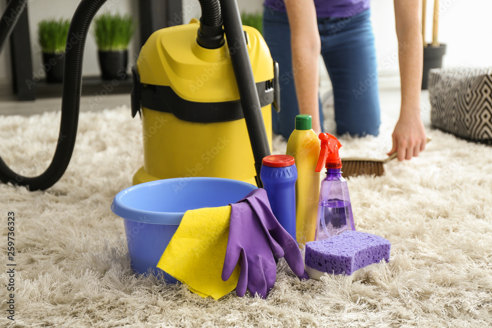 Cleaning supplies with hoover on soft carpet in room