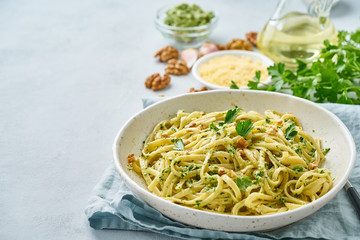 Poster - Pesto pasta bavette with walnuts, parsley, garlic, nuts, olive oil. Side view, copy space, blue background.