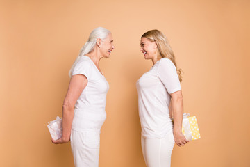 Canvas Print - Profile side view portrait of nice-looking lovely attractive charming cute cheerful cheery positive ladies holding in hands behind back boxes isolated over beige pastel background