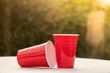 Plastic red solo drinking cups for beer pong or drinking games with green background on a white table.