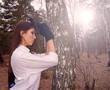 © YAROSLOVEPHOTOVIDEO - Young girl standing near a tree with a gun in the woods.