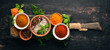 A set of spices and herbs. Indian cuisine. Pepper, salt, paprika, basil, turmeric. On a black wooden chalkboard. Top view. Free copy space.