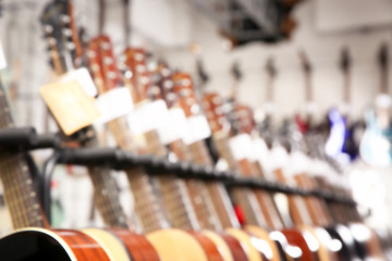 Wall Mural - Row of different guitars in music store, blurred view