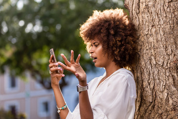 Wall Mural - Outdoor portrait of a Young black African American young woman texting  on mobile phone