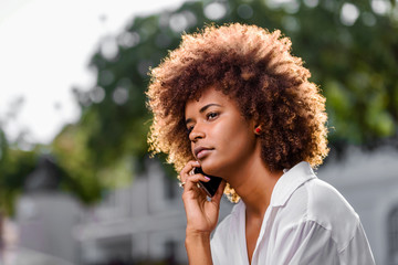 Wall Mural - Outdoor portrait of a Young black African American young woman speaking on mobile phone