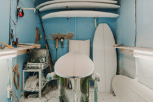 Workplace With Wooden Surf Boards Near Shelf With Carpenter Planes And Different Weapons