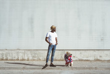 Stylish Black Man With Labrador Wrapped In Colorful American Flag On Concrete Street In Sunlight