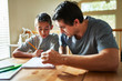© Joshua Resnick - father helping son with homework on table at home