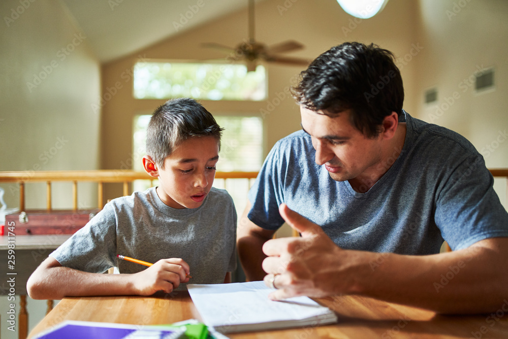 father helping son with homework on table at home Stock Photo | Adobe Stock