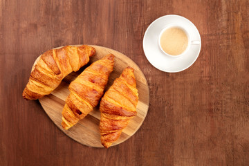 Wall Mural - A French breakfast with croissants and coffee, shot from the top on a dark rustic wooden background with a place for text