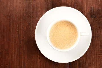 Poster - A cup of coffee with froth shot from the top on a dark rustic wooden background with a place for text