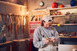 © astrosystem - Male carpenter fixing old wood in a retro vintage workshop.
