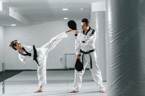 Plakaty Taekwondo  niepelnosprawna-rasy-kaukaskiej-wysoce-zmotywowana-dziewczyna-cwiczaca-taekwondo-podczas-treningu-dziewczyna-kopiaca