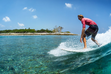 Wall Mural - Happy surfer rides the funny, crystal clear, tropical wave