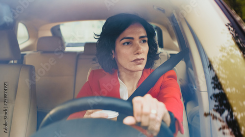 Fotografía Portrait of Serious Beautiful Young Woman Driving Car through Sunny Suburban Area