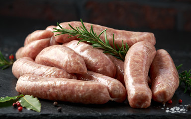 Wall Mural - Freshly made raw butchers sausages in skins with herbs on stone board