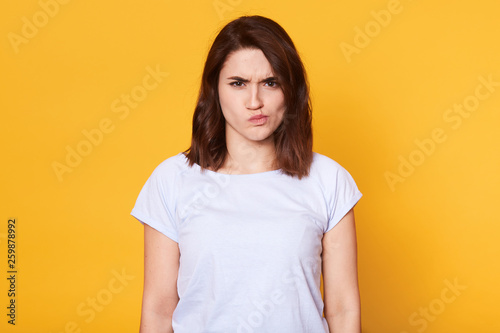 Portrait Of Angry Young Woman Frowning Over Yellow Background Looks Offened Has Unpleasant Facial Expression Has Bad News Brunette Female Wears Casual T Shirt Poses In Photo Studio Copy Space Stock Photo Portrait Of Angry Young Woman Frowning Over Yellow Background Looks Offened Has Unpleasant Facial Expression Has Bad News Brunette Female Wears Casual T Shirt Poses In Photo Studio Copy Space Stock Photo