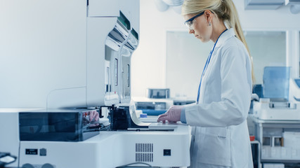 Wall Mural - female research scientist putting test tubes with blood samples into analyzer medical machine. scien